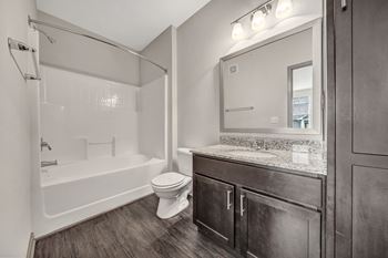 A bathroom with a white tub, toilet, and sink.